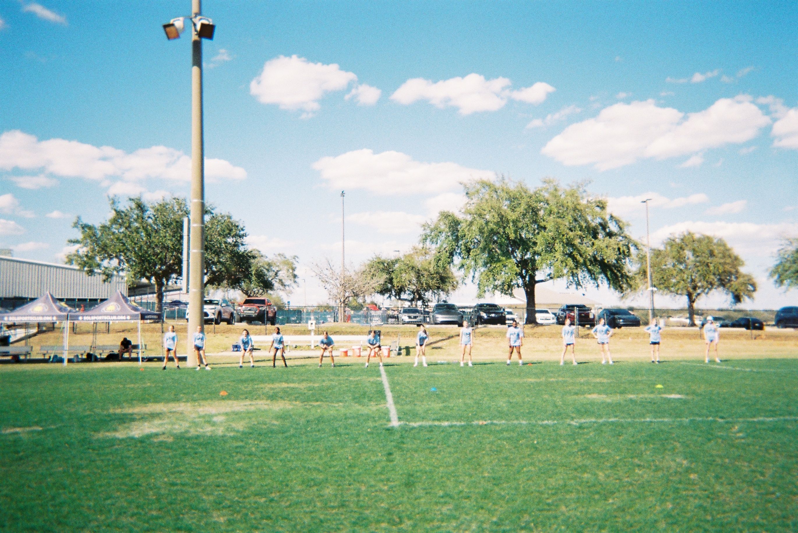 Girls standing along the sideline of a soccer pitch during a warm up.
