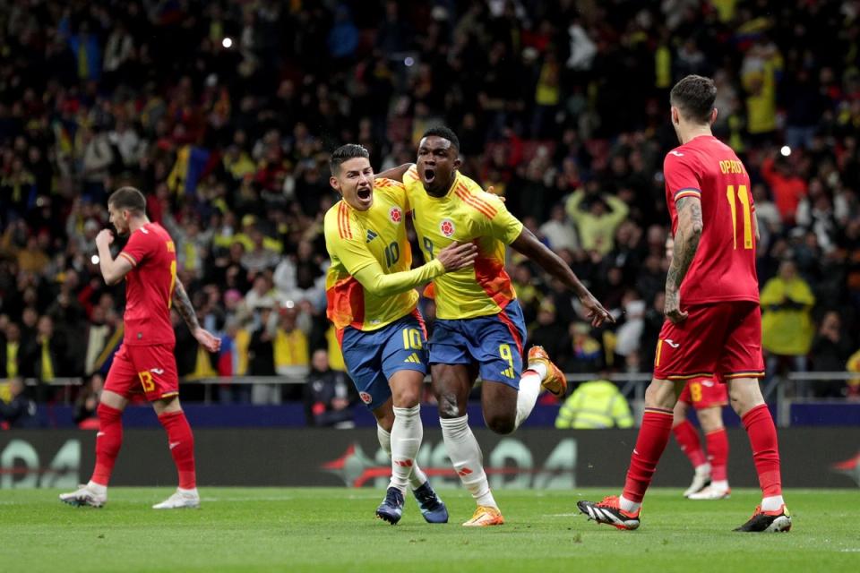 two Colombian players in yellow kits and blue shorts celebrate running through the midfield during a match