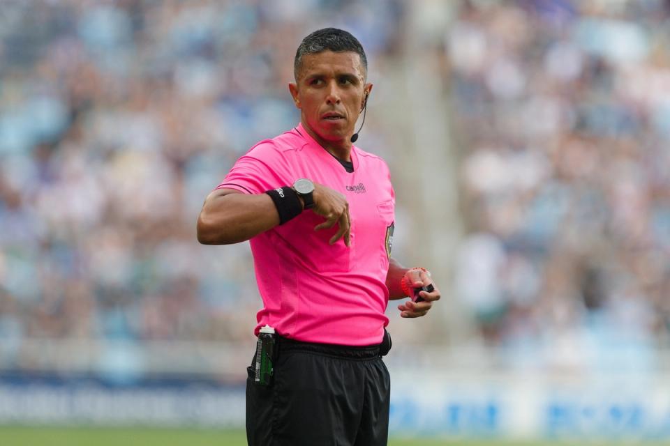 A referee in a pink shirt on the pitch