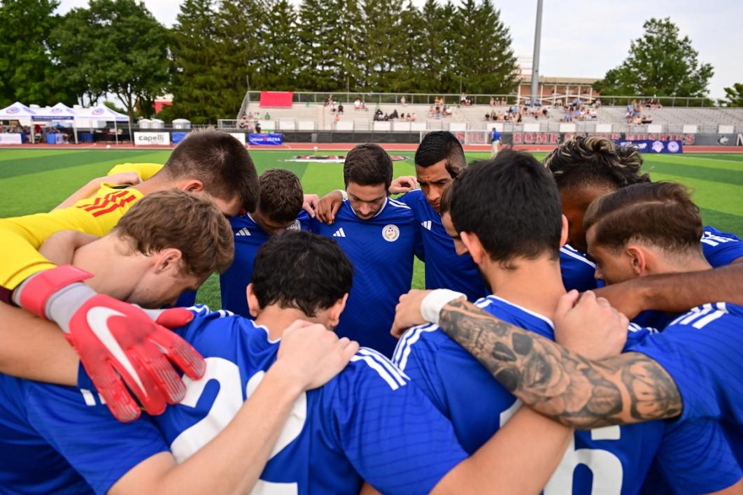 photo of team in blue huddled together