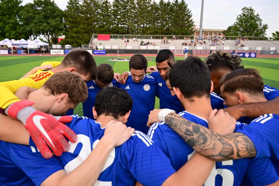 photo of team in blue huddled together