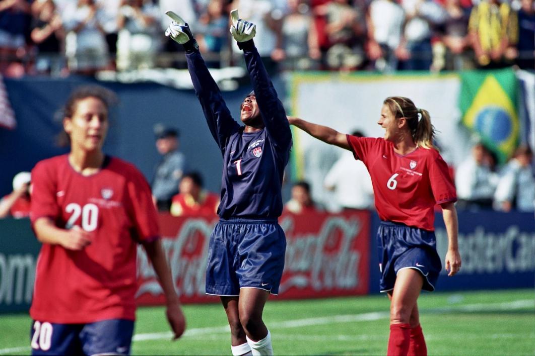 uswnt goalkeeper in blue points to the sky and yells in celebration