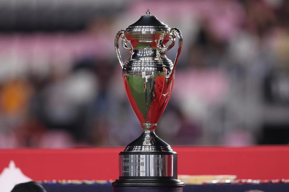 A photo of the US Open Cup trophy with a blurred stadium background
