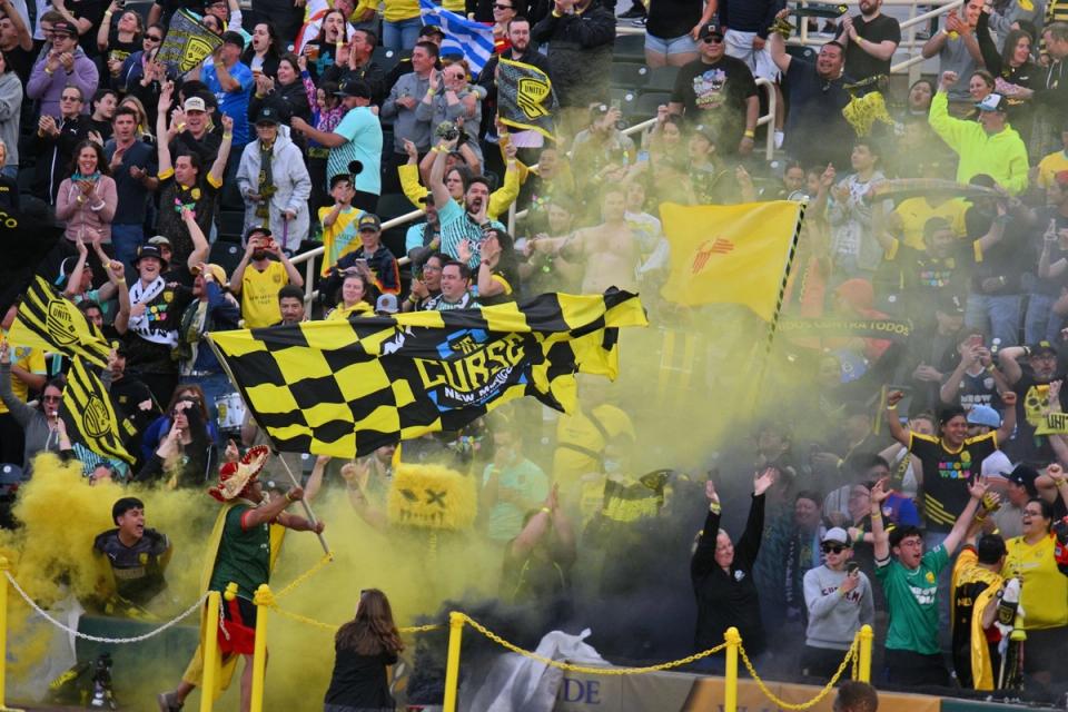 NMU Supporters in the crowd with yellow smoke and a flag that says The Curse