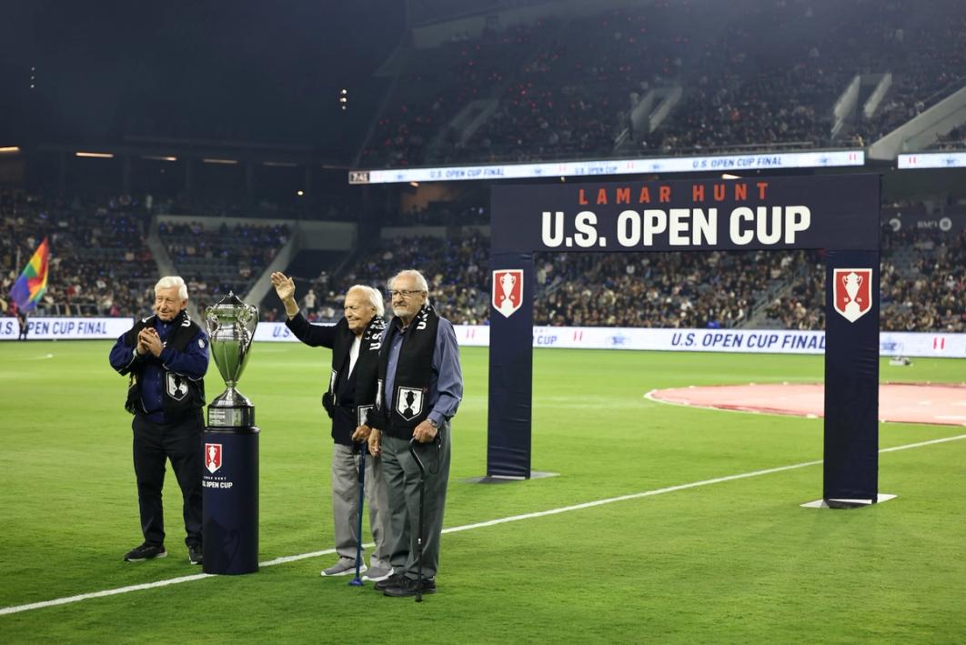 Members of the 1958 and 1964 LA kickers flank the trophy on the field during the 2024 Final