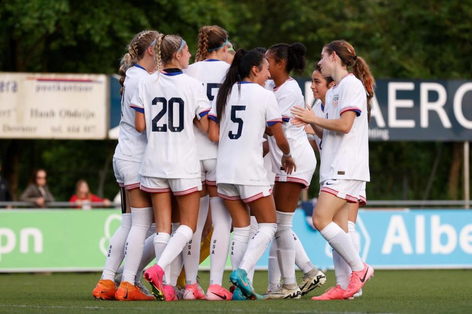 Players on the US U15 Girls National Team huddle in celebration on the field during a match
