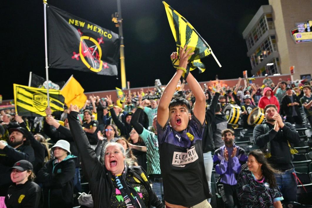 New Mexico United fans cheer waving flags in the crowd