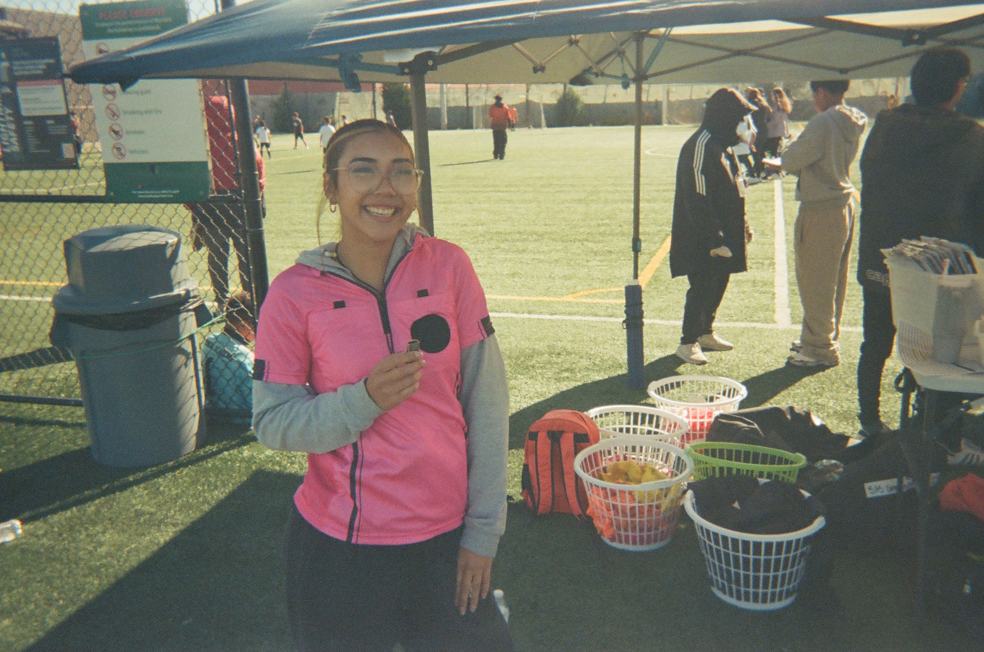 Volunteer smiling beside a community soccer field during a youth soccer event.