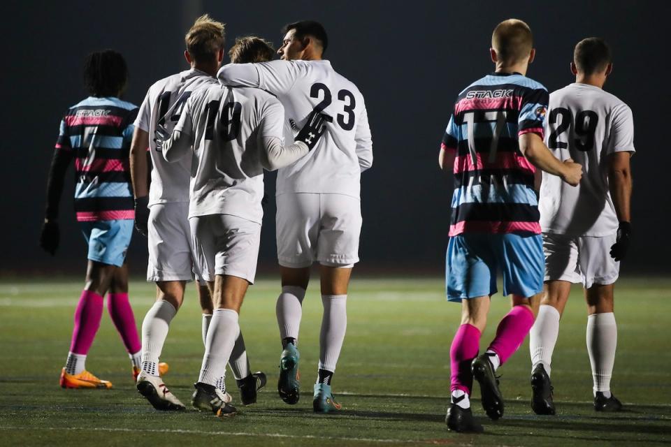 Teammates in white embrace during a 2025 U.S. Open Cup Qualifying Match