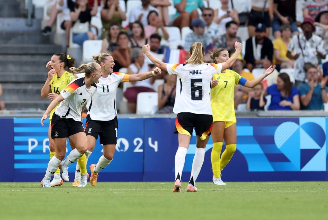 Three members of the German National Team celebrate on the field during an Olympic match
