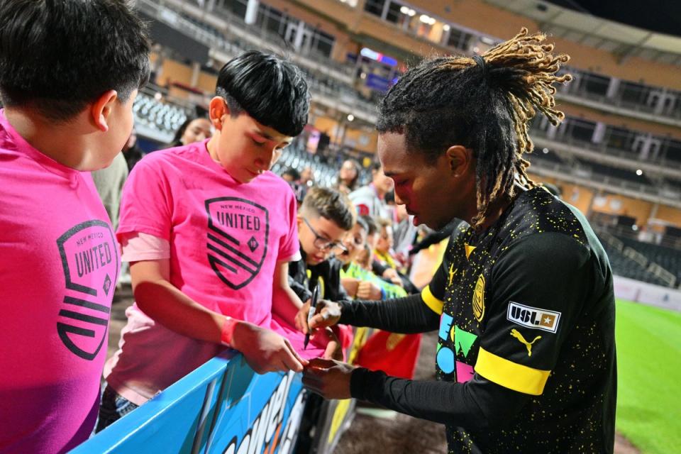 Zico Bailey signing an autograph for a young New Mexico Untied fan