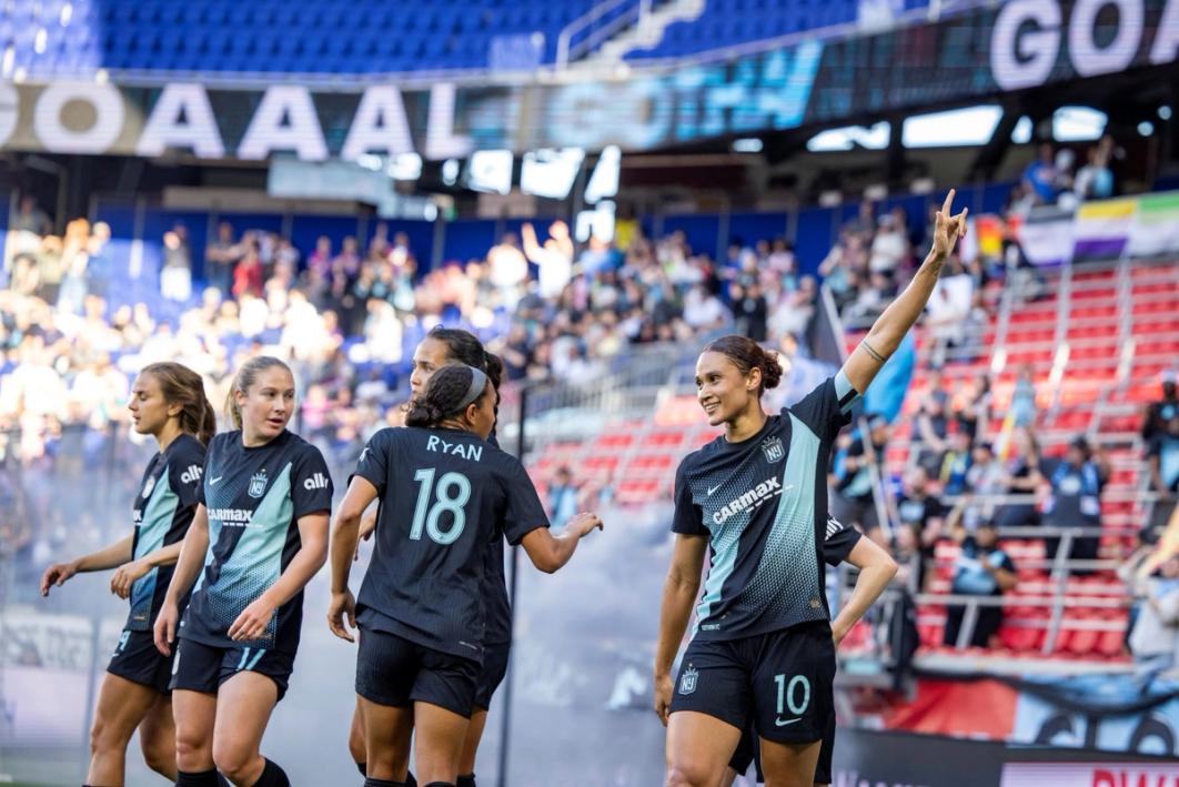 Lynn Williams waves to the crowd during a Gotham FC match with teammates to her left and crowd in the background