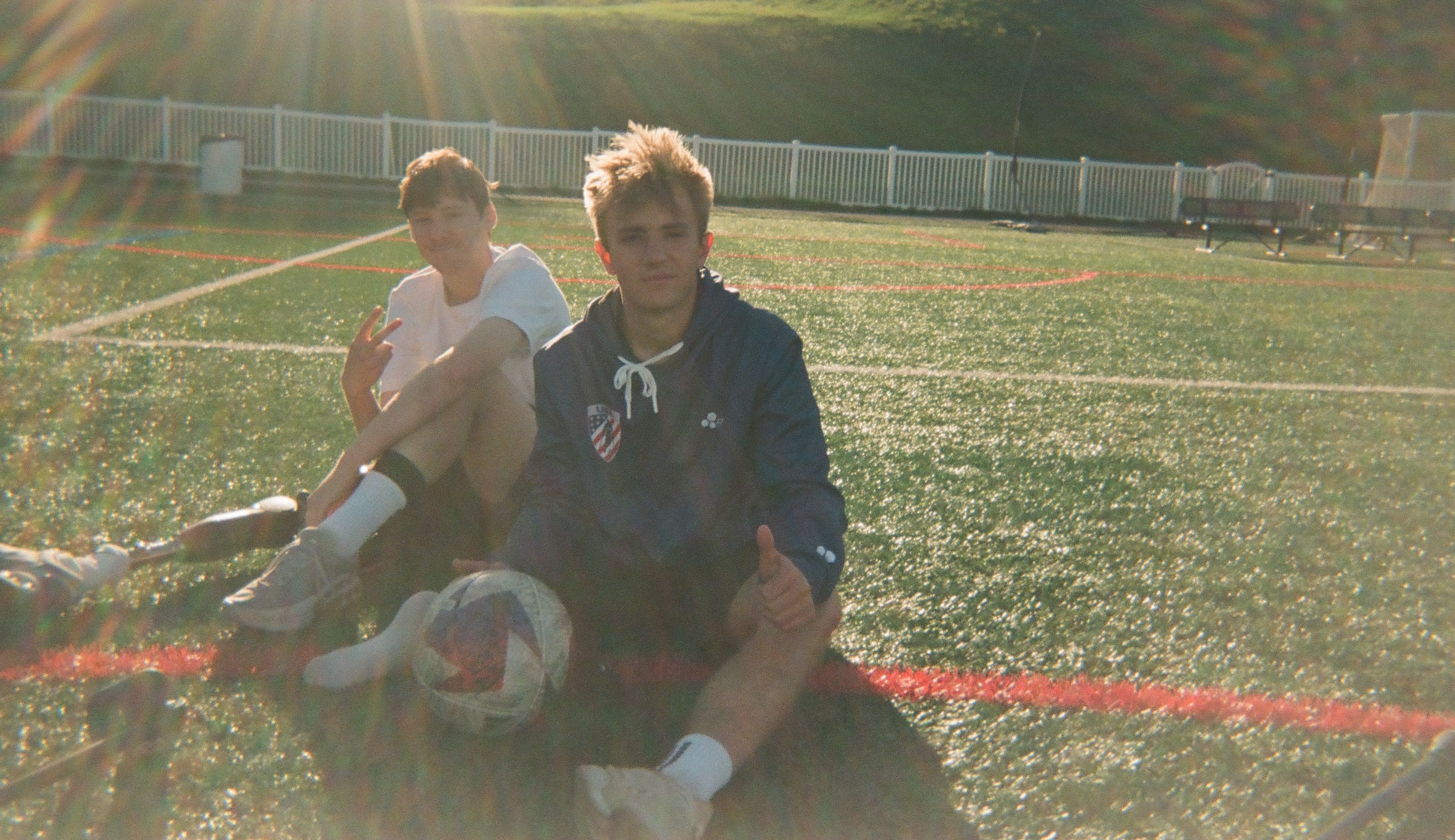Two youth soccer players sitting on a field after training.
