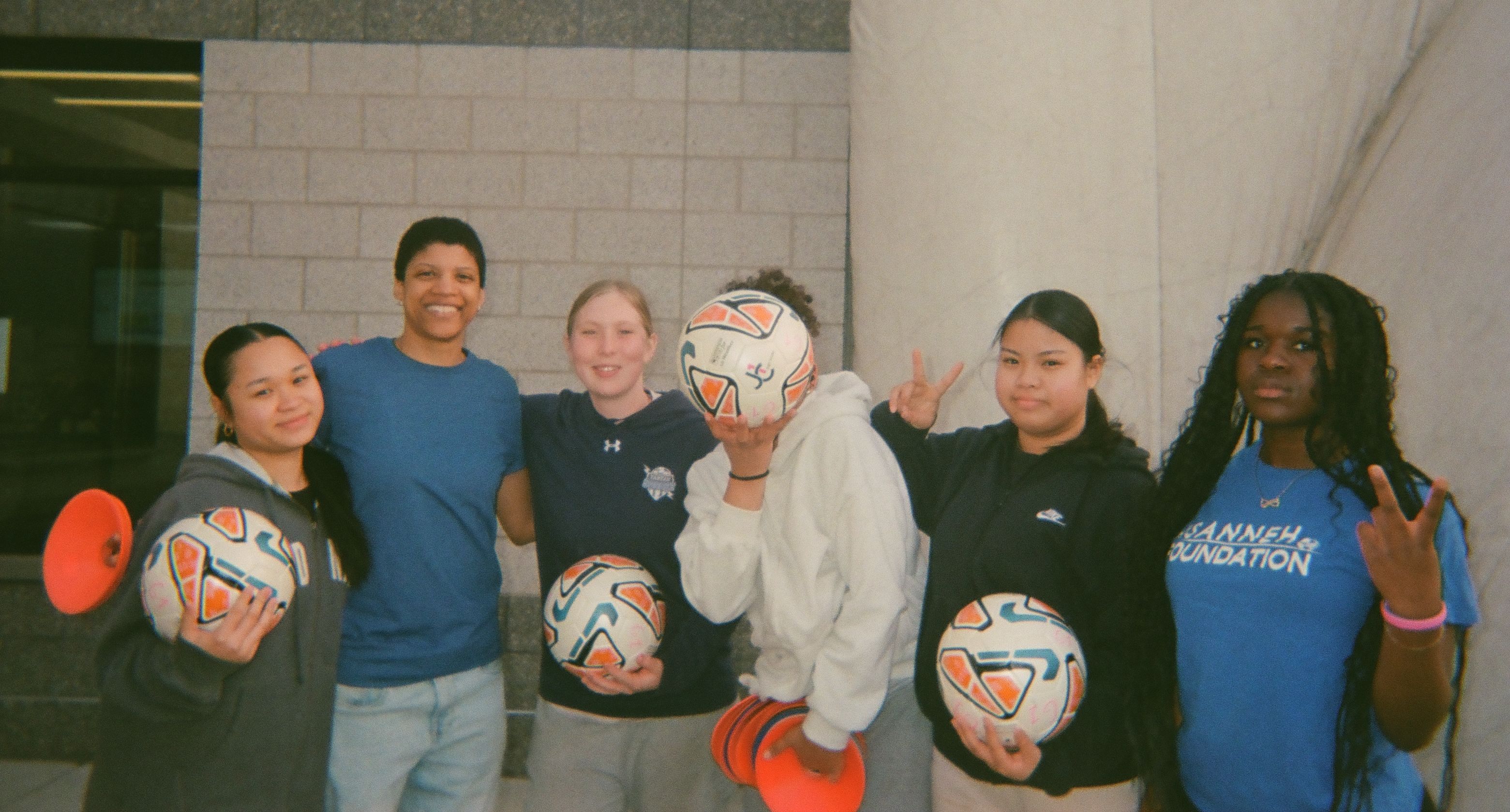 A group of girls at soccer practice posing for a photo.