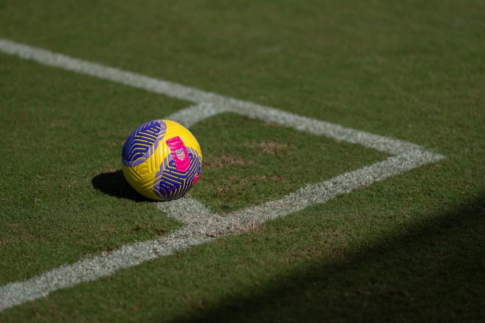 A Yellow and purple soccer ball placed on a soccer field