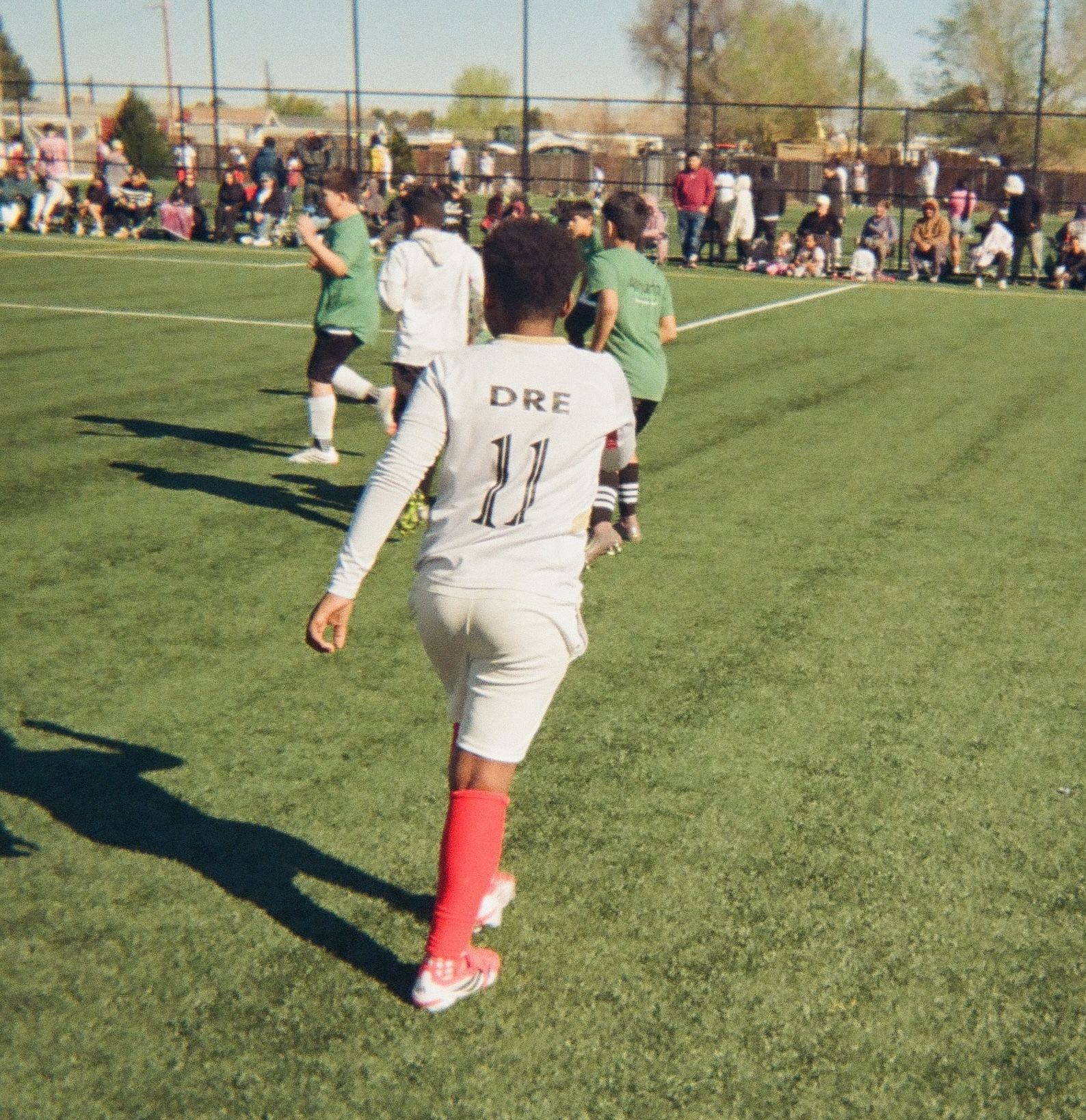 Youth soccer players competing on a field with families watching from the sidelines.