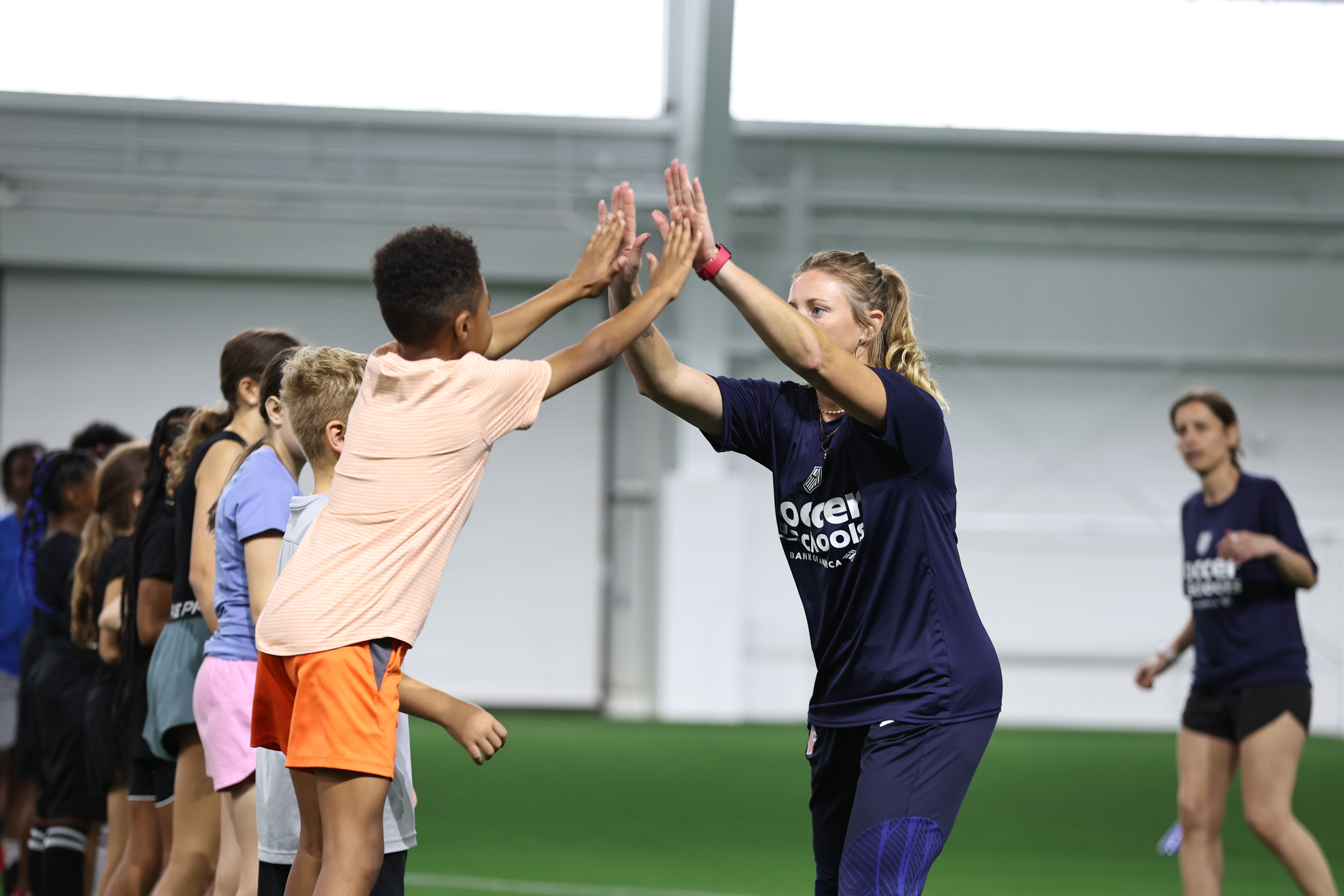 Coach high-fiving children during an indoor soccer session.