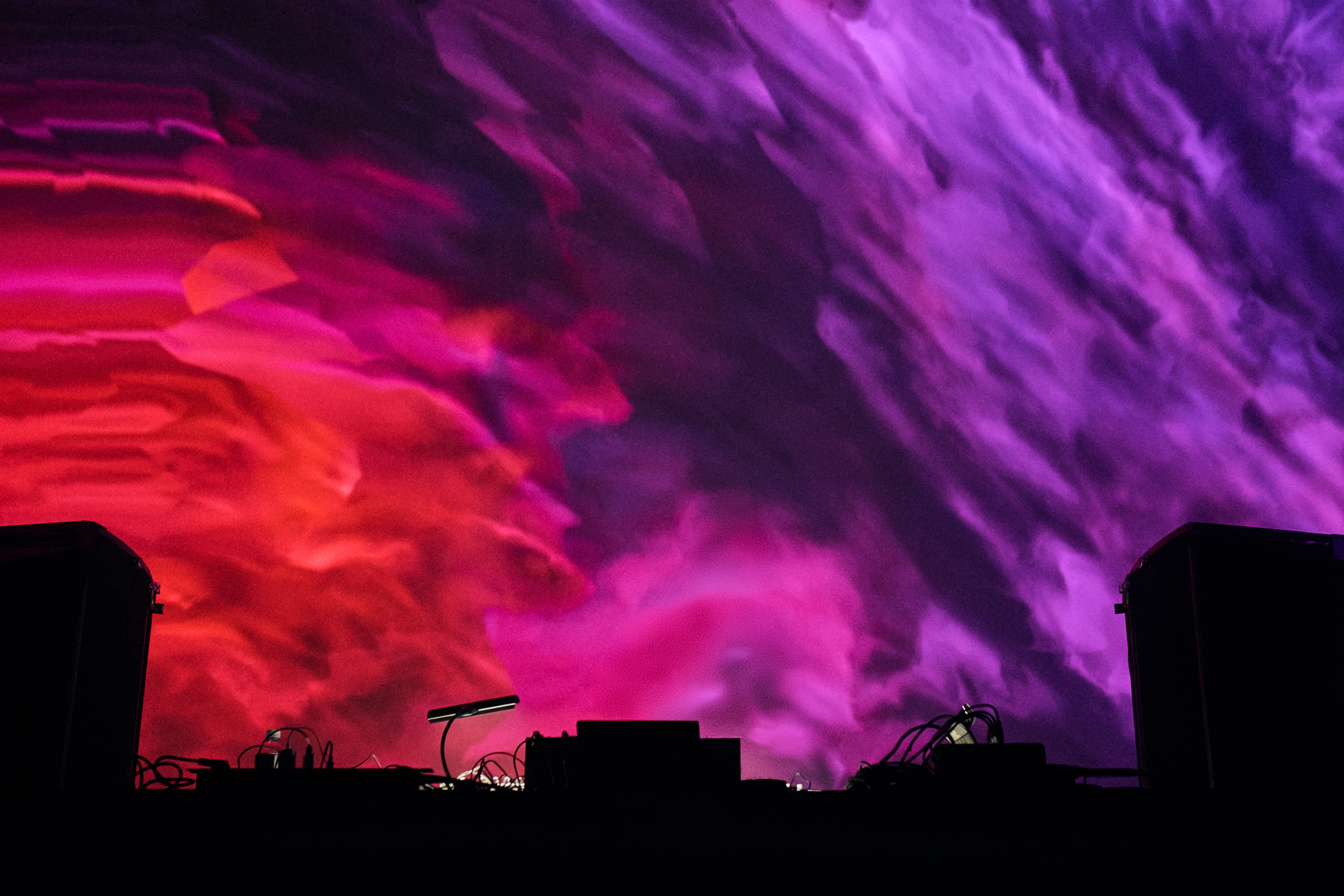 Blurred red and purple haze behind a DJ booth.