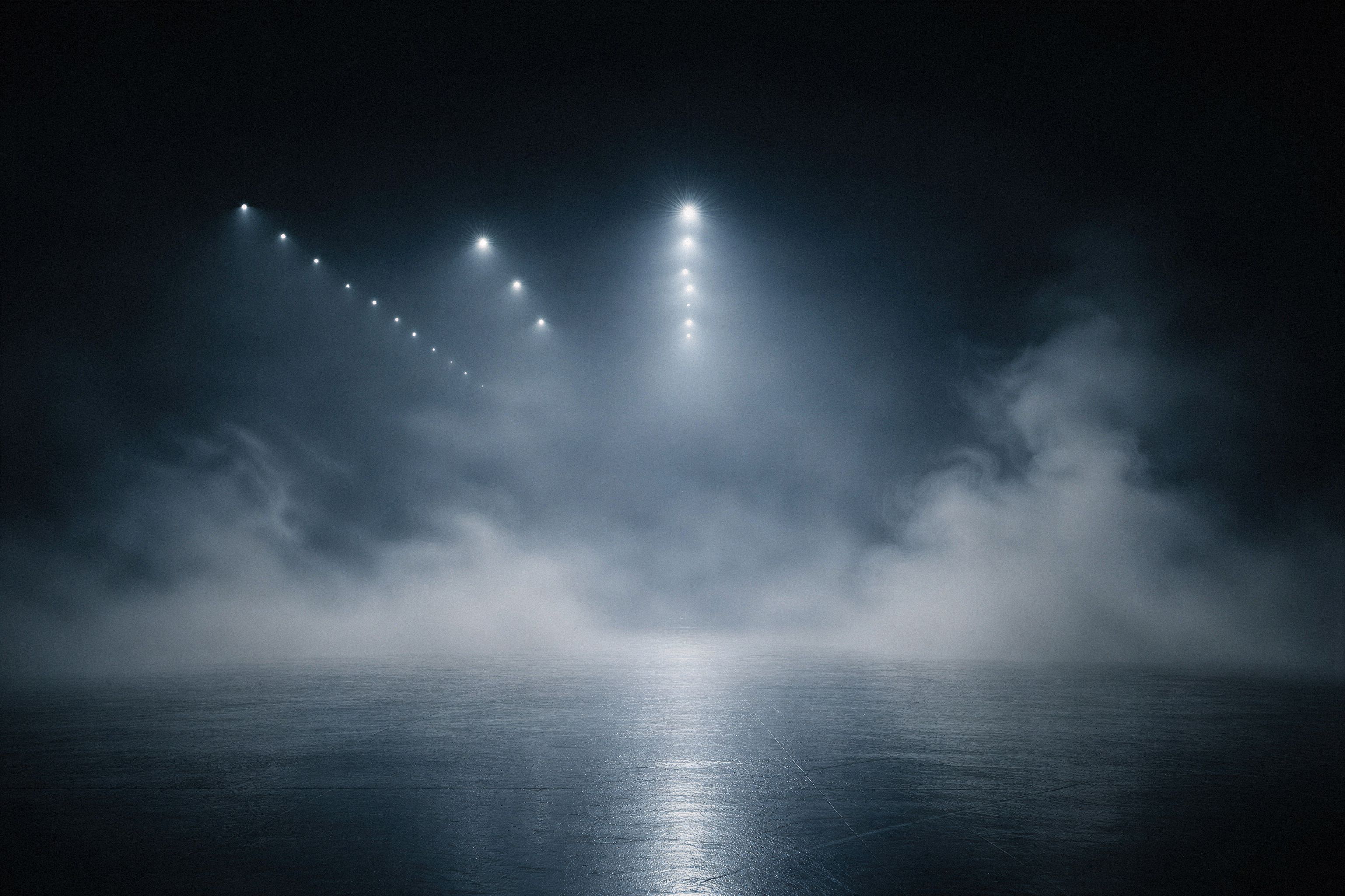 A series of overhead spotlights pierce through a thick, swirling fog in a dark, cavernous space, reflecting off a polished floor. The minimalist lighting and dense mist create a cold, atmospheric, and cinematic environment.