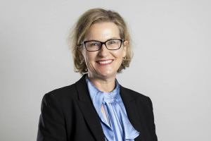 a woman wearing glasses and a blue shirt smiles for the camera