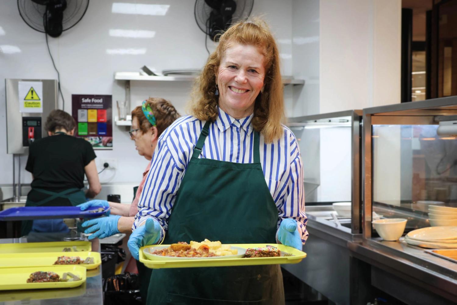 a woman wearing an apron is smiling in a kitchen
