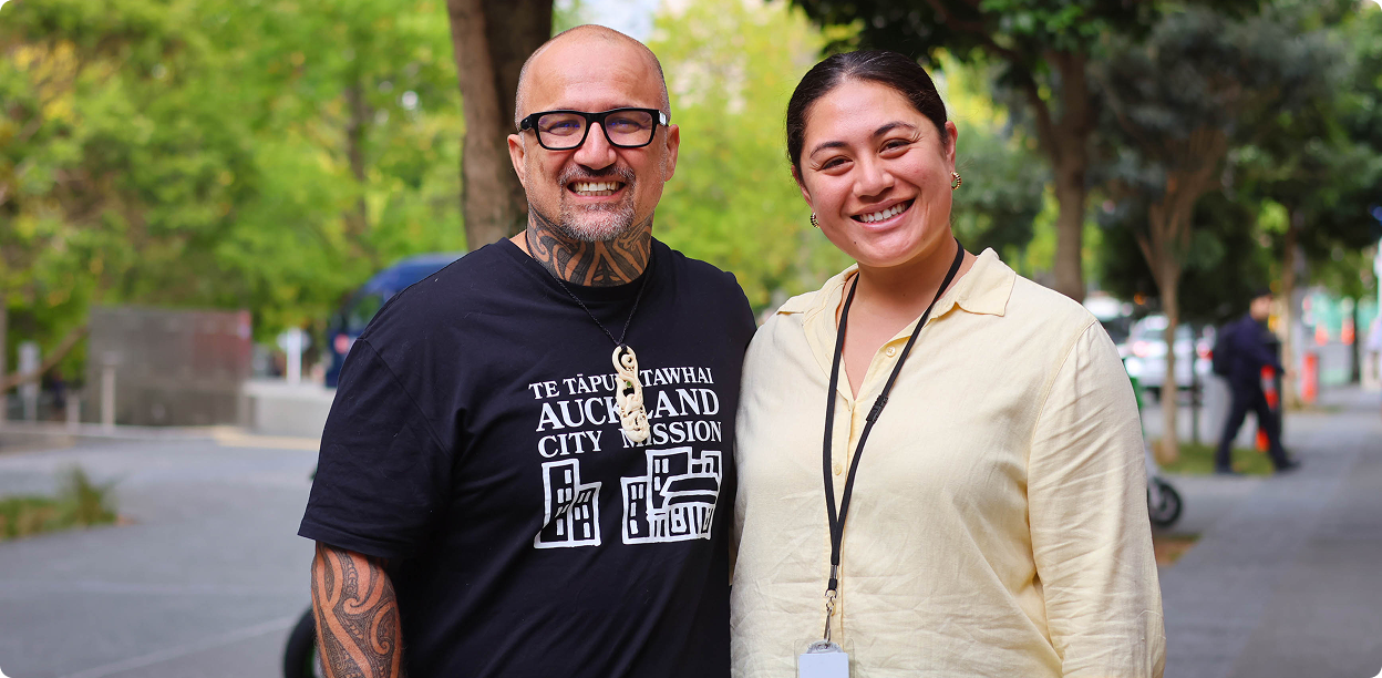 a man and a woman are posing for a picture and the man is wearing a shirt that says auckland city mission