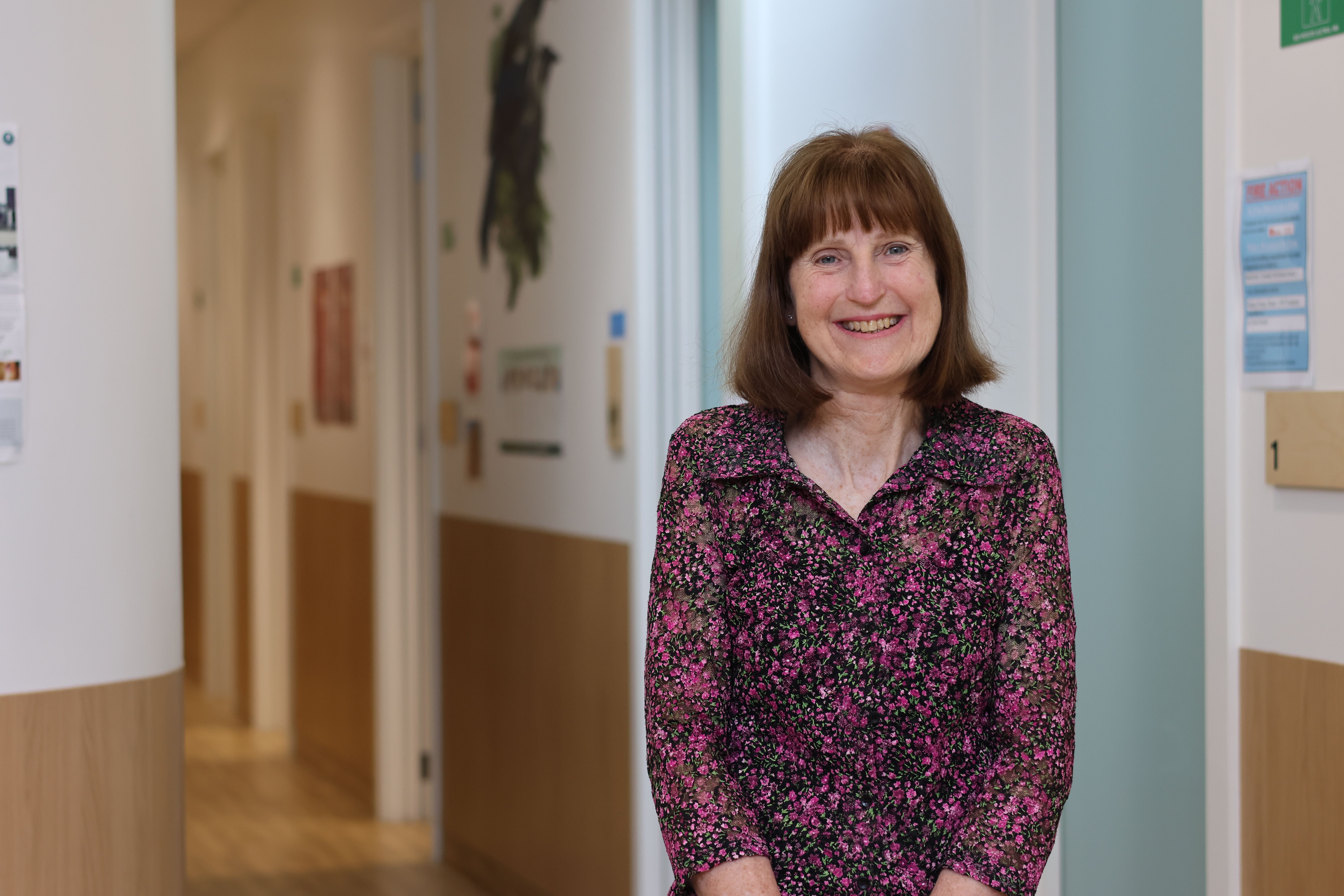 a woman is standing in a hallway smiling at the camera .