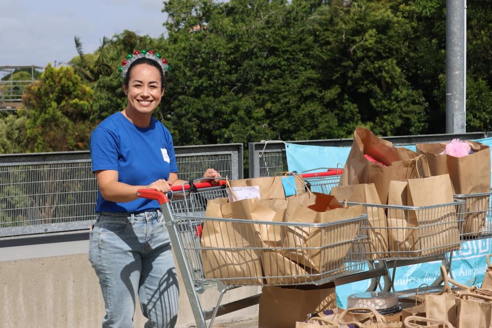 a woman with a christmas festive headband on holding a trolly filled with paper bags