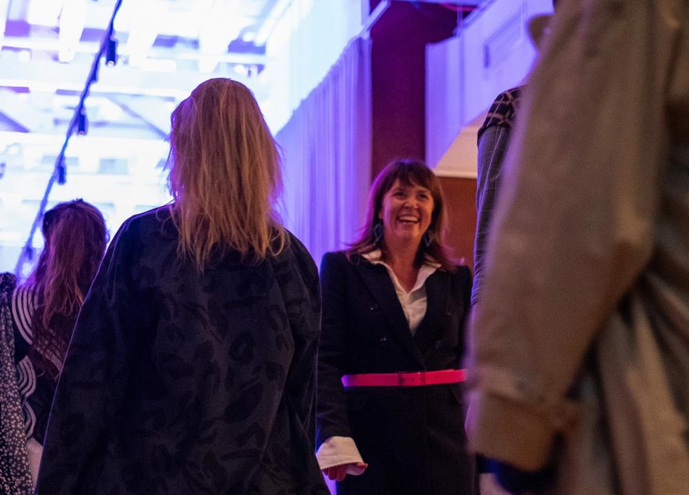 a woman wearing glasses and a necklace is smiling in front of a white house .