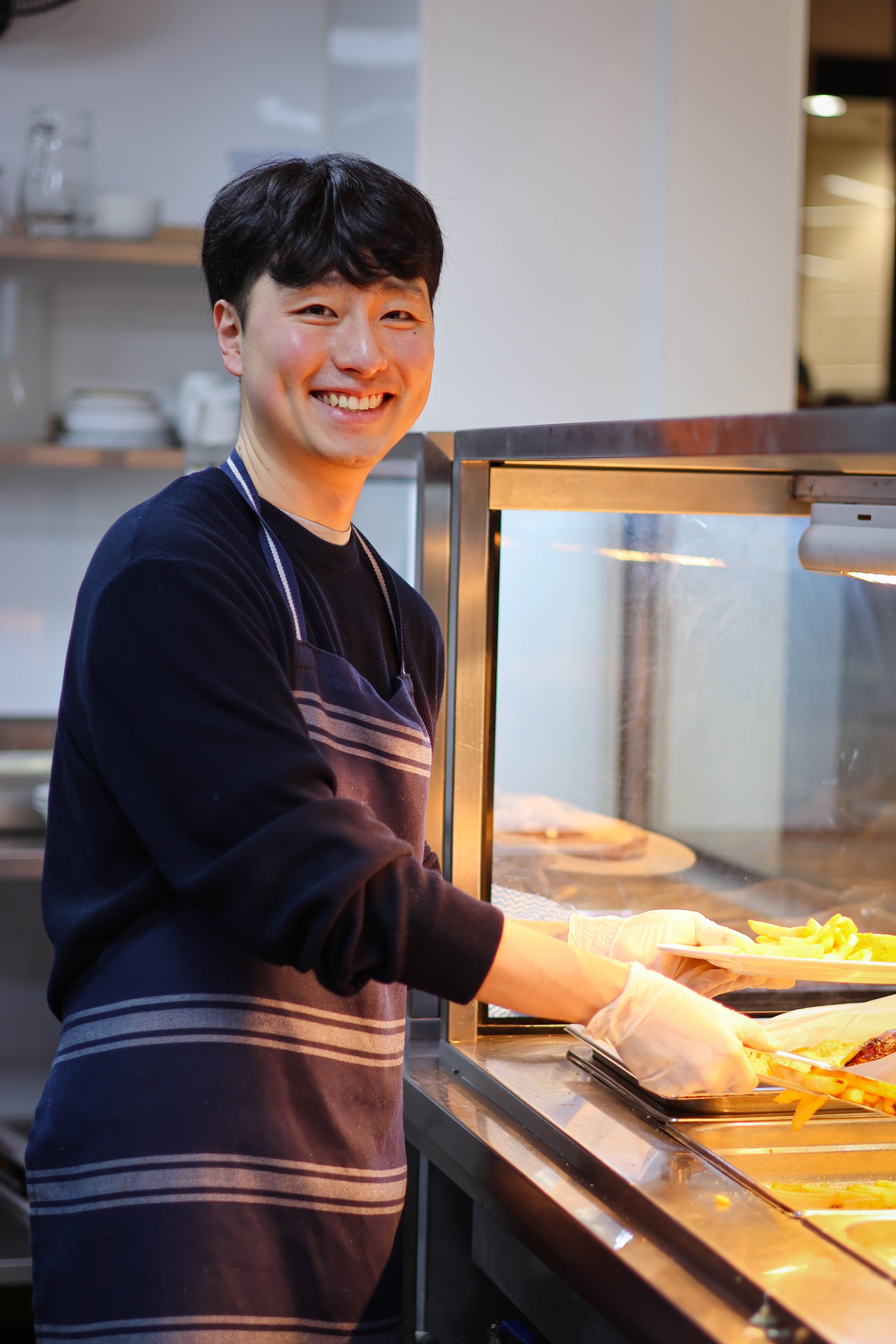 a woman wearing an apron is smiling in a kitchen