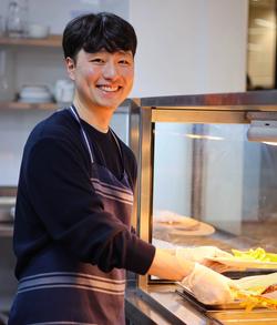 a woman wearing an apron is smiling in a kitchen