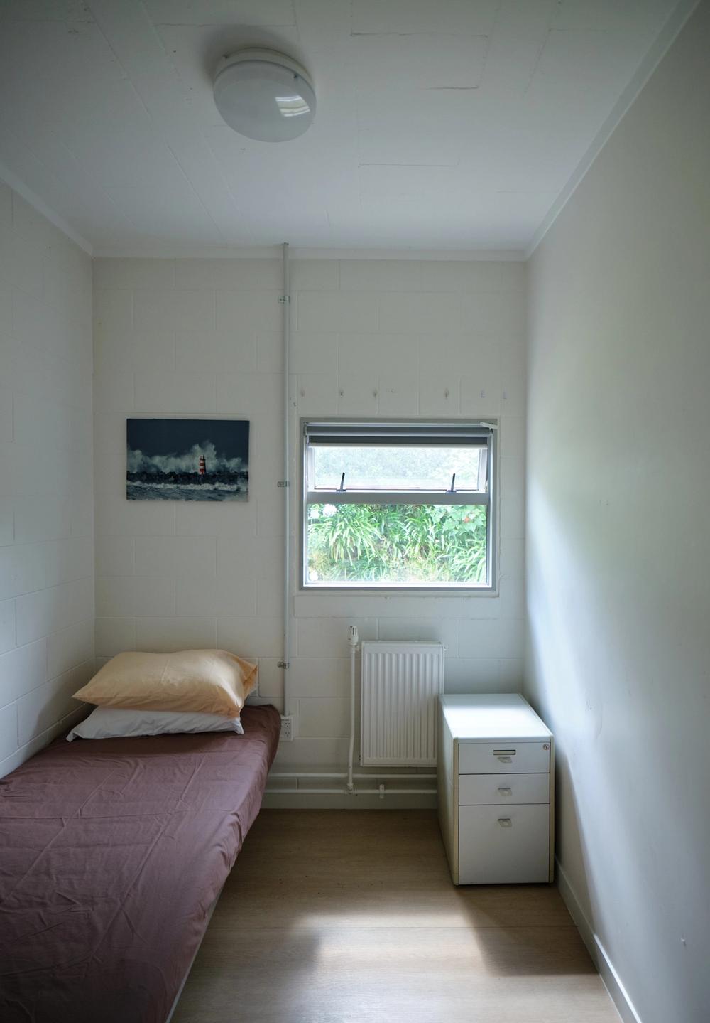 a woman wearing glasses and a necklace is standing in front of a white house .