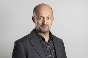a man in a suit and polka dot shirt looks at the camera