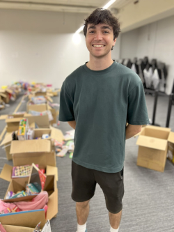 a man in a green shirt stands in front of a pile of cardboard boxes
