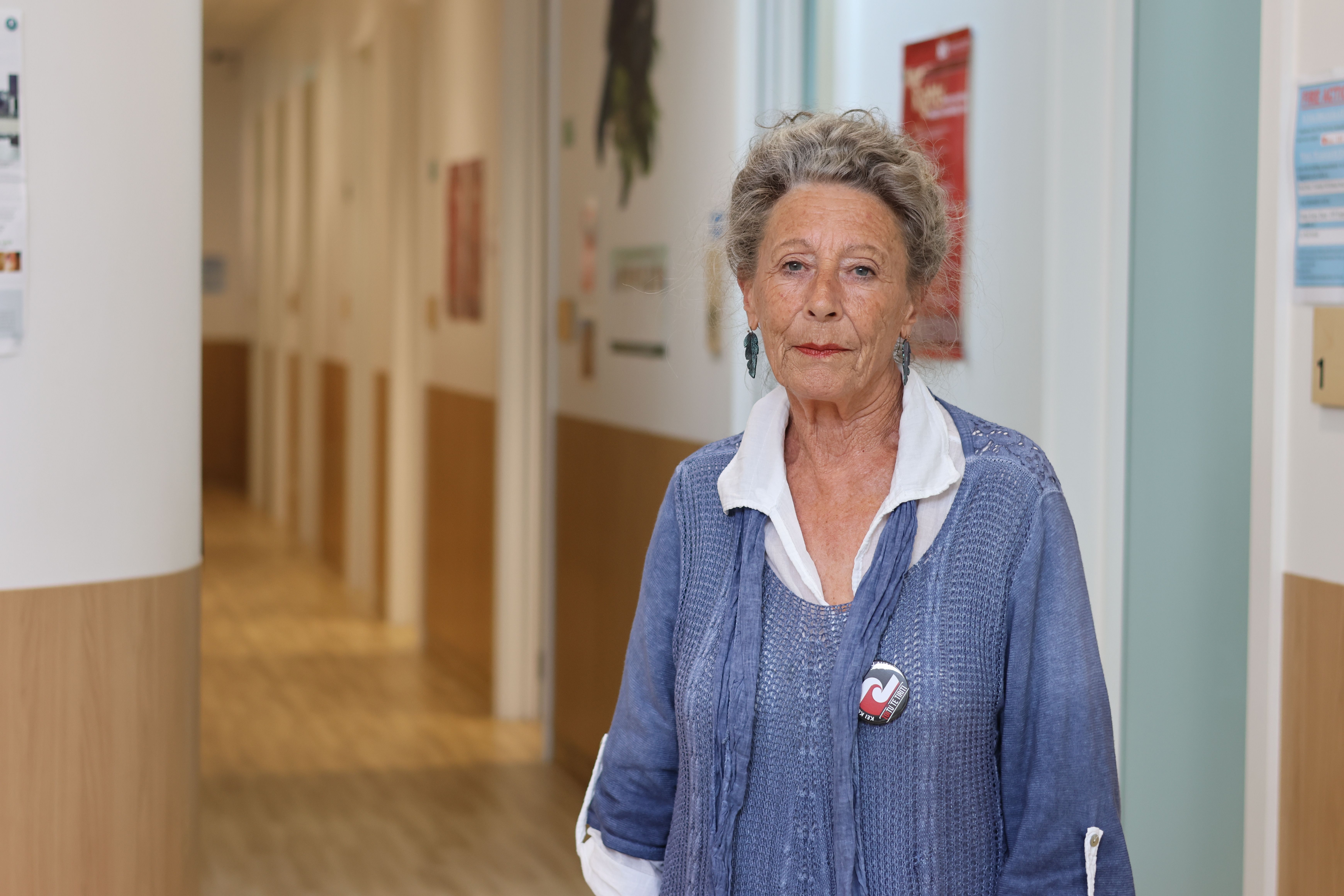 a woman is standing in a hallway wearing a blue sweater and a white shirt .