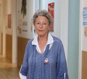 a woman is standing in a hallway wearing a blue sweater and a white shirt .