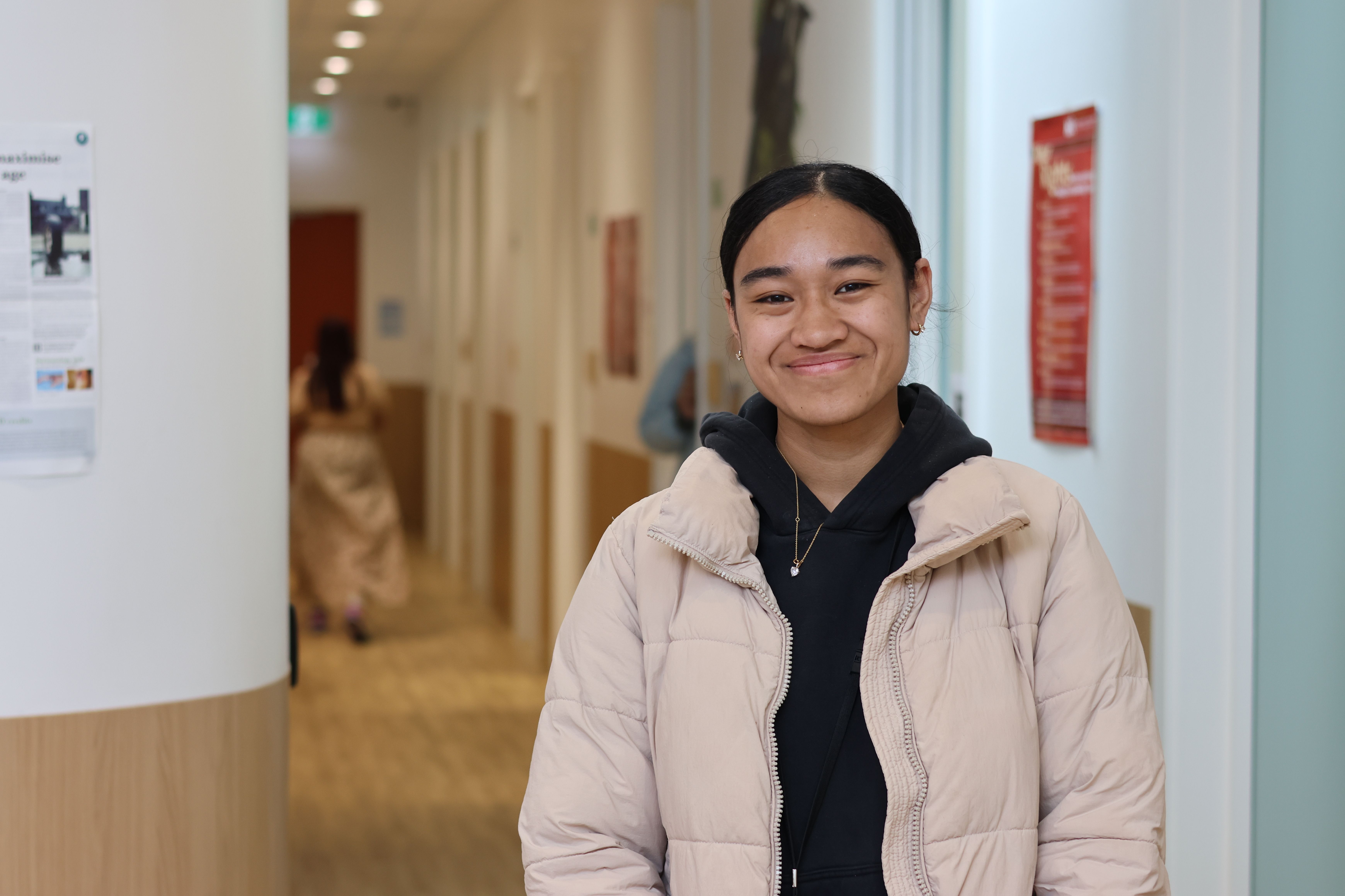 a young woman is standing in a hallway smiling at the camera .