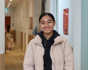 a young woman is standing in a hallway smiling at the camera .
