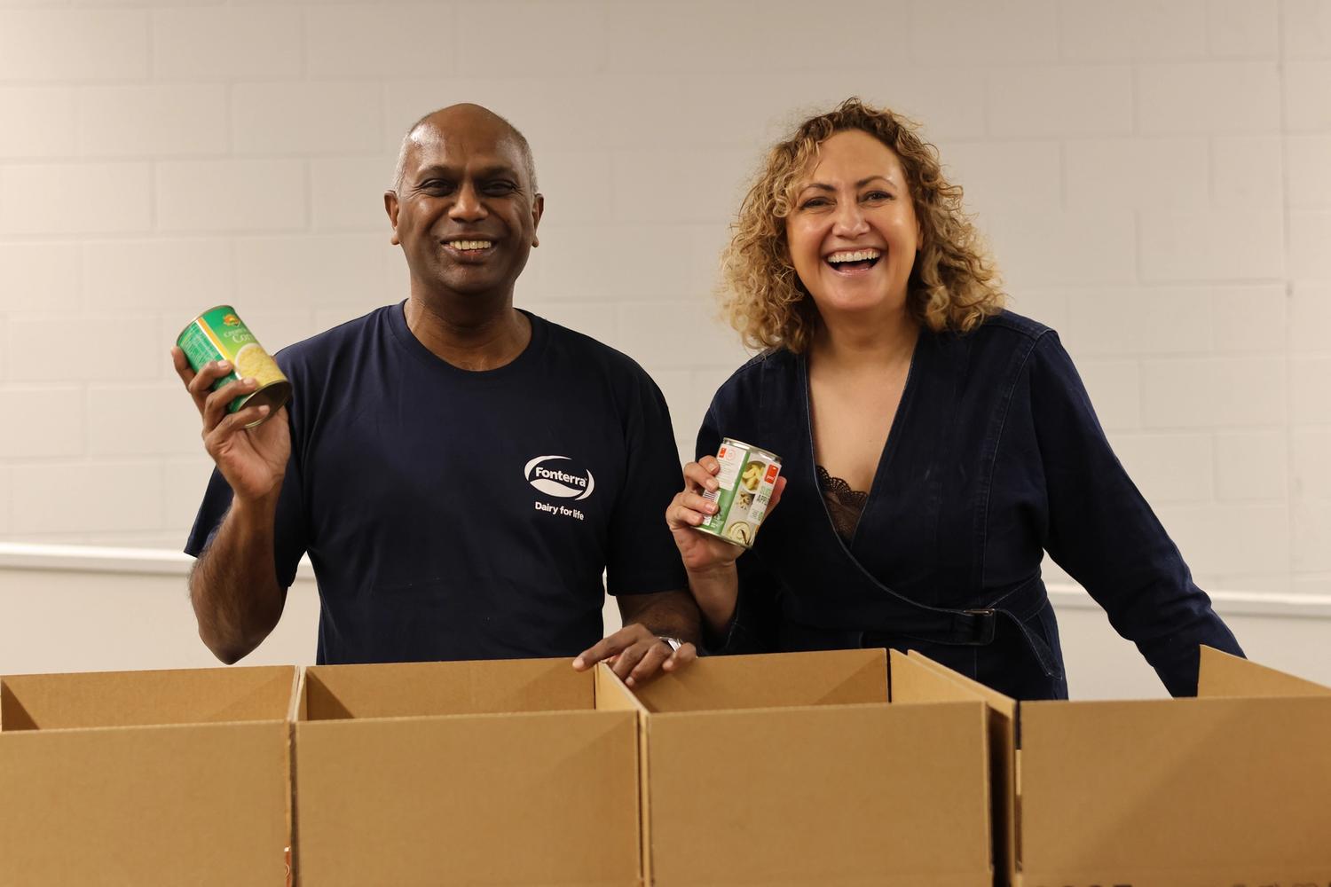 a man and a woman are standing next to each other holding cans of food .