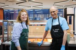a man and a woman wearing aprons are standing next to each other in a kitchen .