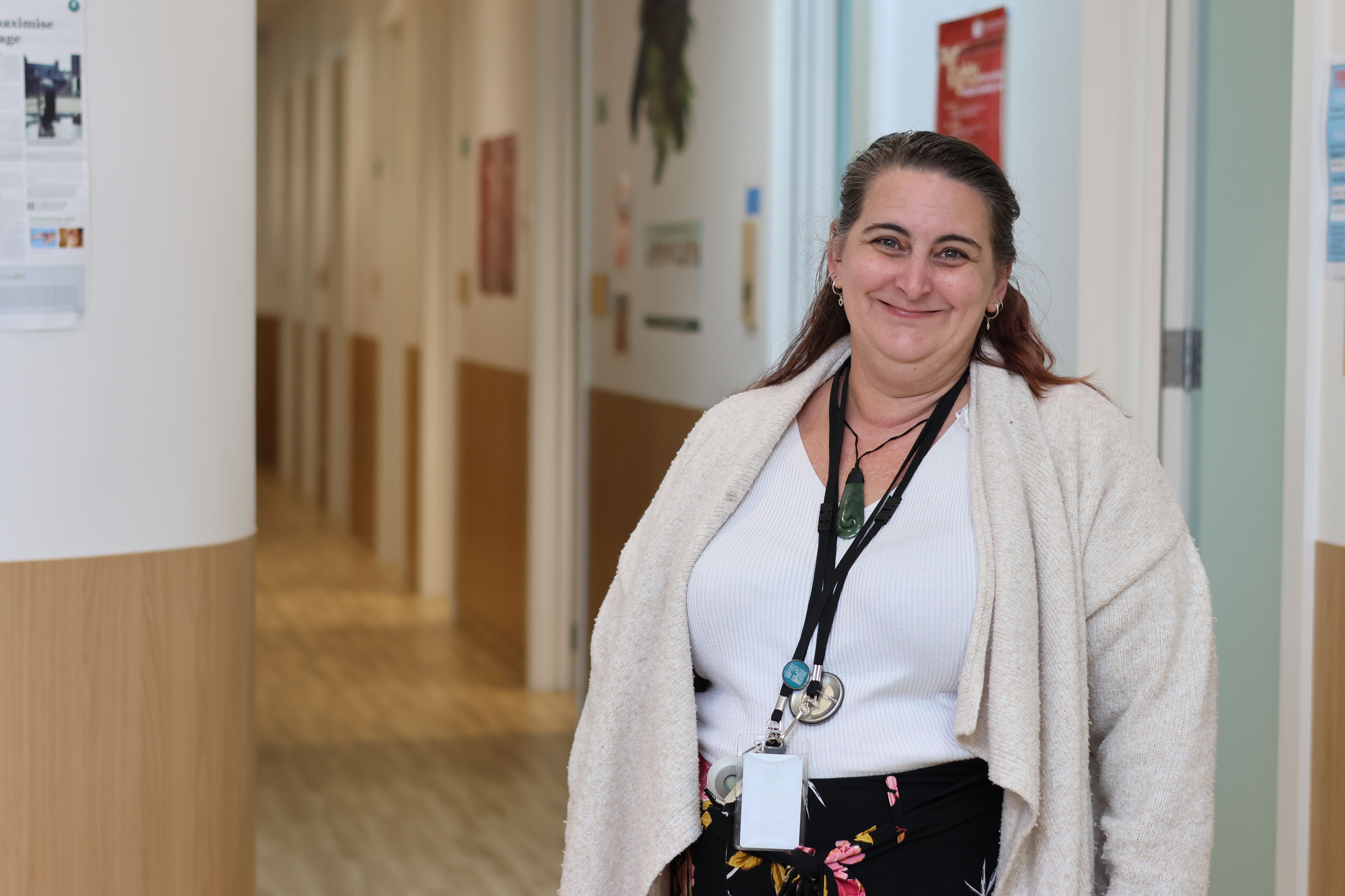 a woman is standing in a hallway wearing a lanyard and smiling .