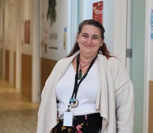 a woman is standing in a hallway wearing a lanyard and smiling .