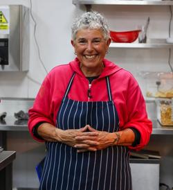 a woman wearing an apron is smiling in a kitchen