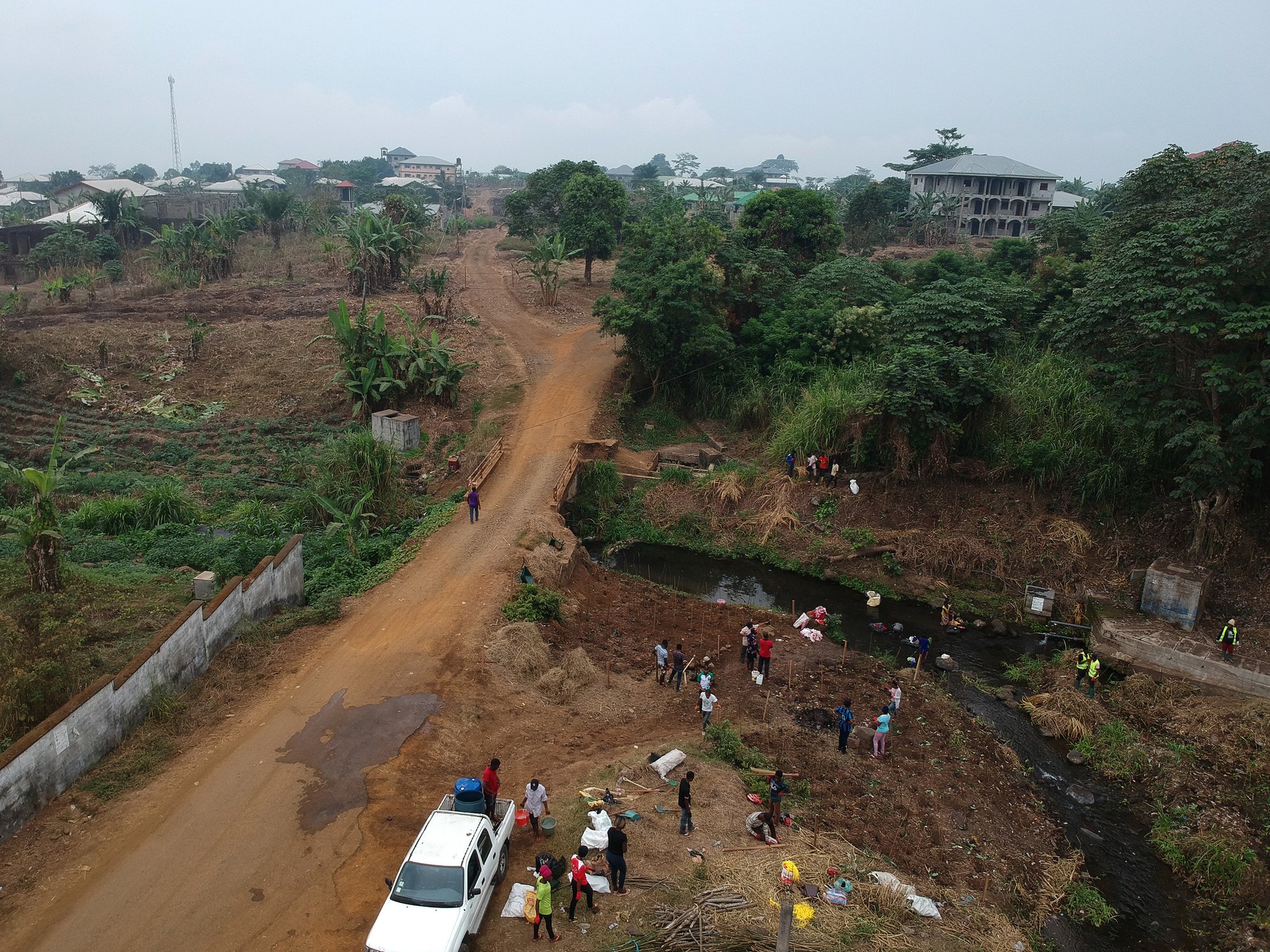 people stand near a river in a dirt field