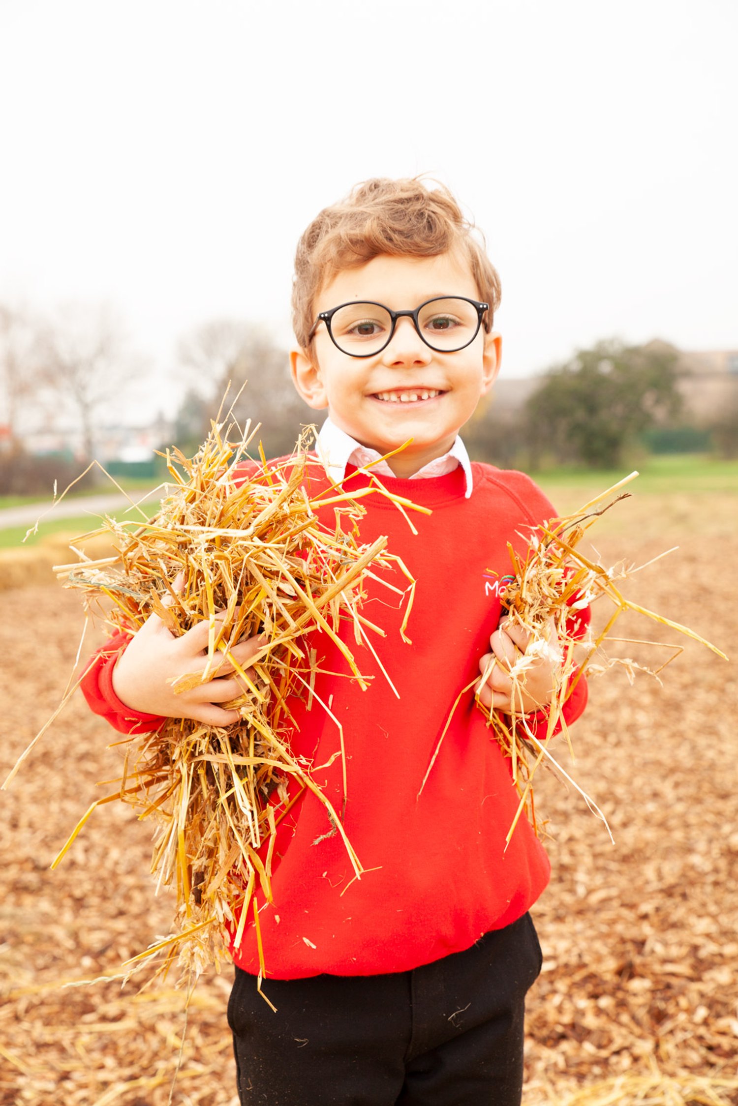 a boy holds hay and smiles