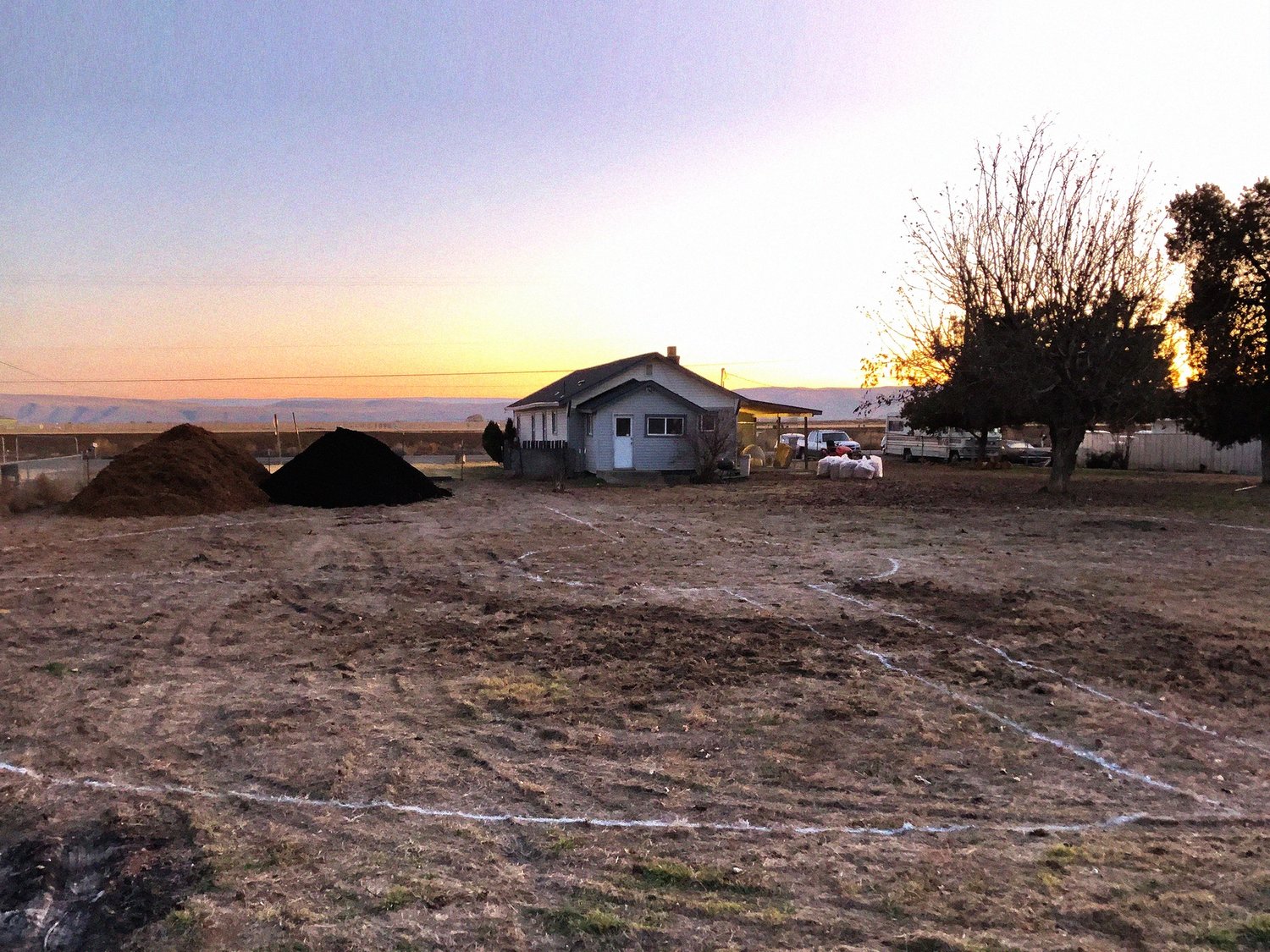 white lines drawn in the dirt with a house in the background