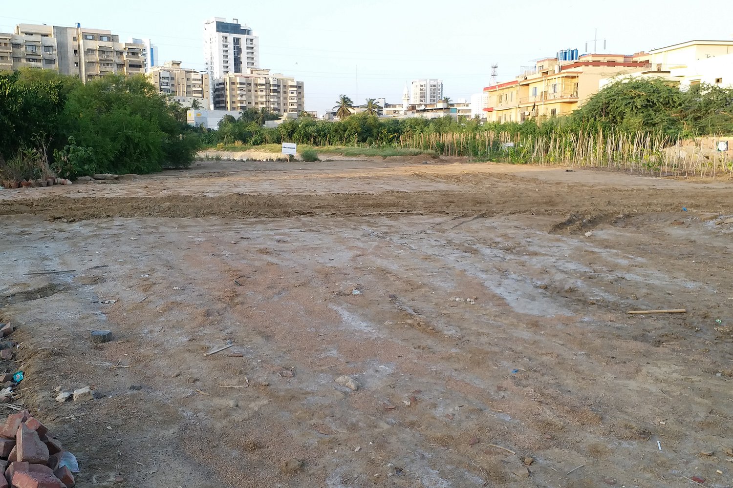 a dirt field with building in the background