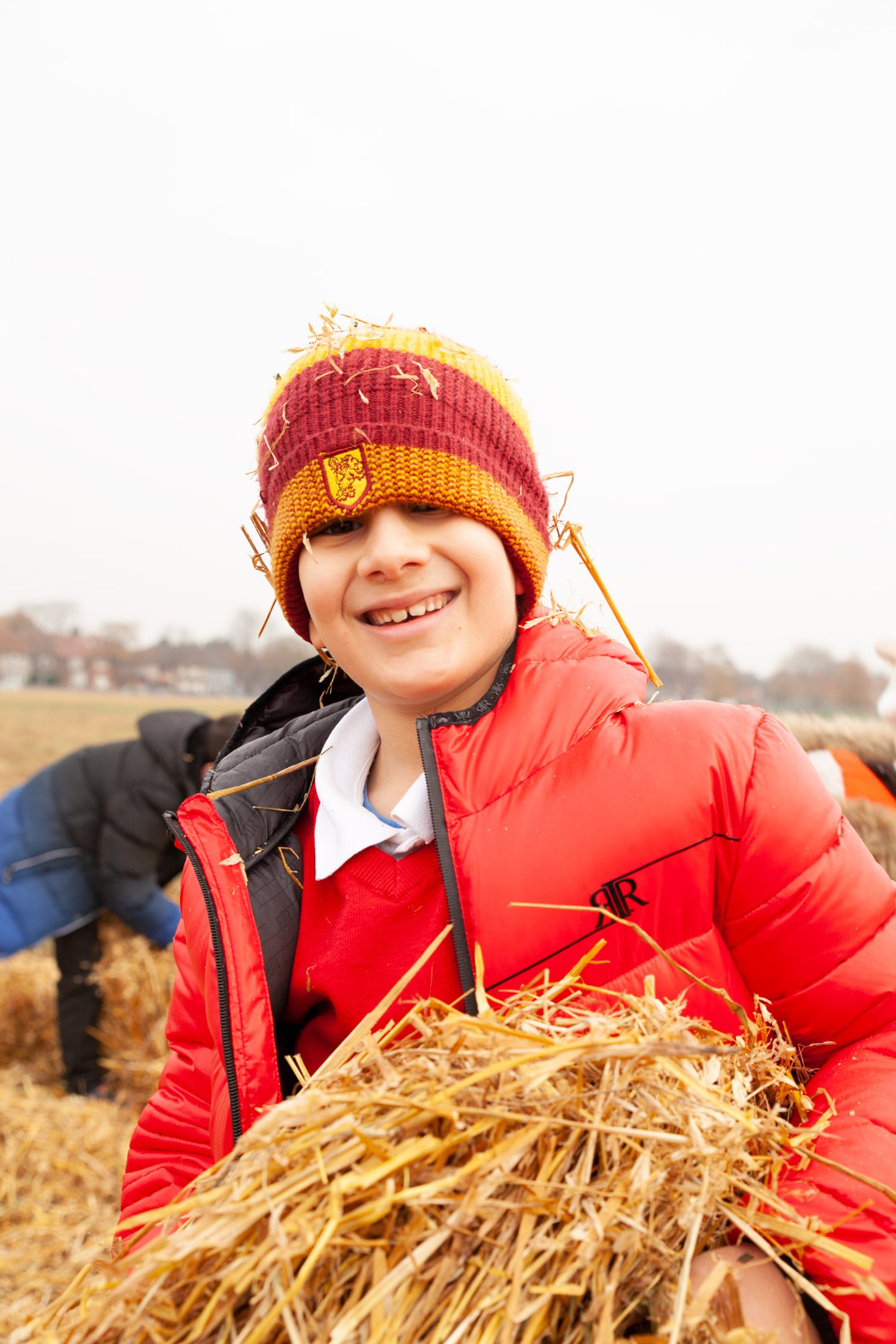 a boy holds hay and smiles