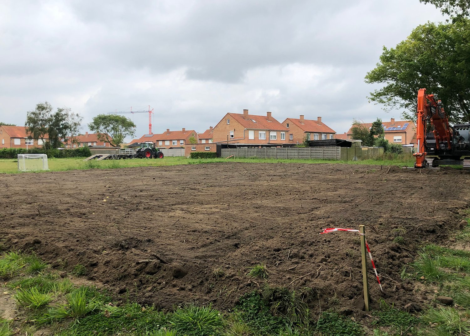 a dirt field with. ahouse in the background