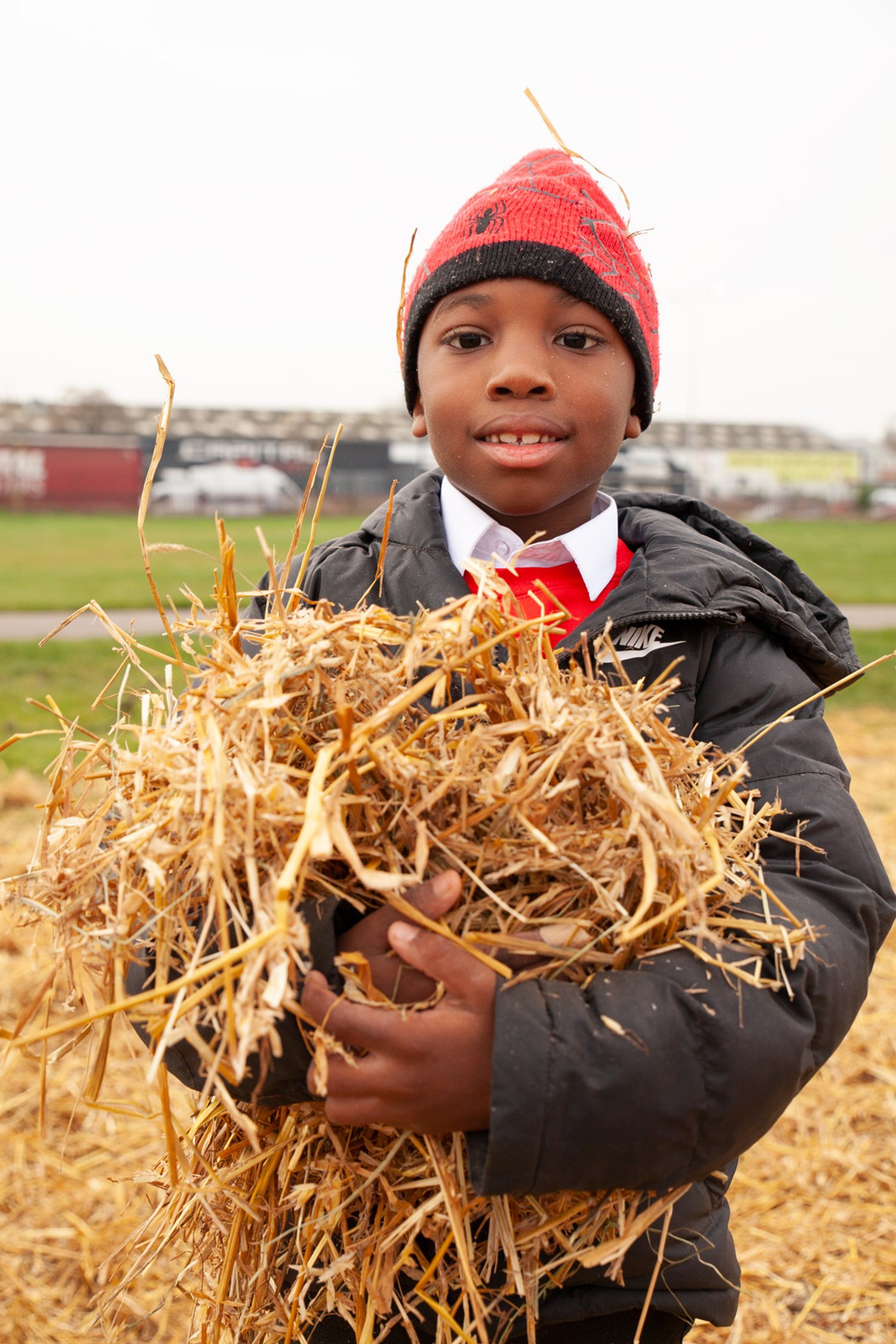 a boy holds hay and smiles